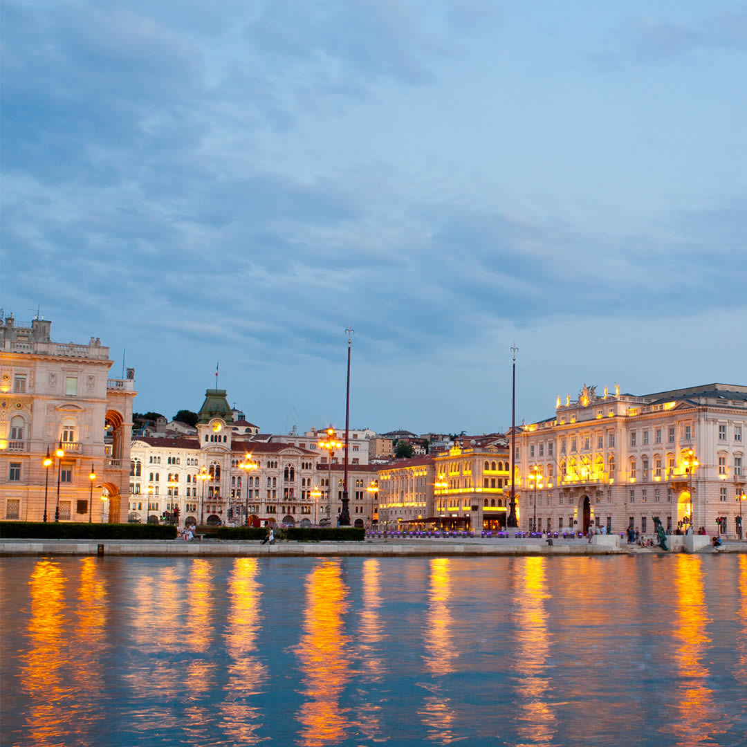 Piazza Unità d'Italia a Trieste al tramonto, con il Municipio e le luci riflesse sul mare