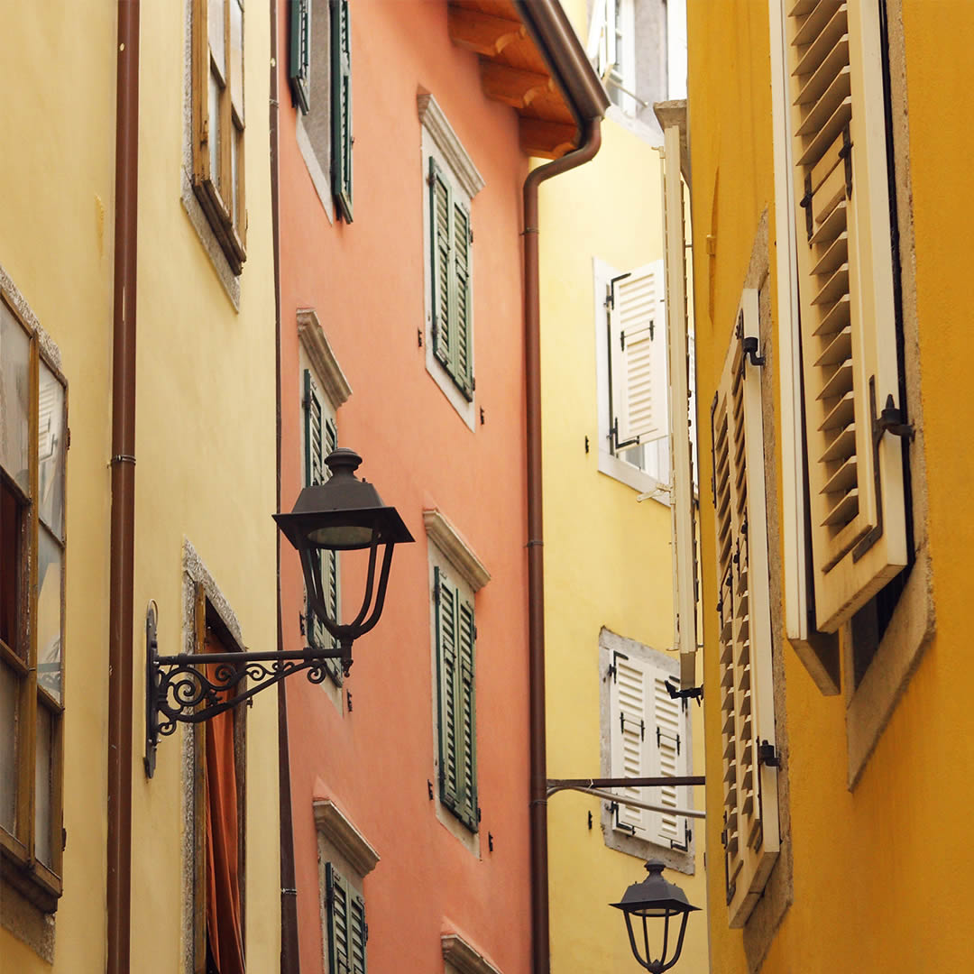 Una via stretta di Cittavecchia a Trieste, con le facciate color ocra e un lampione in ferro