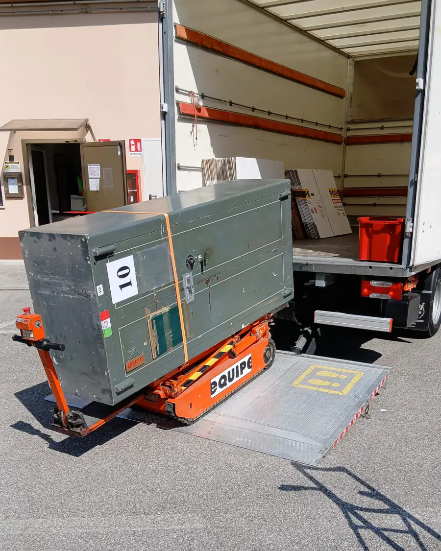 Trasloco di uffici e aziende: una cassaforte sul carrello cingolato Equipe viene caricata dalla sponda idraulica del camion