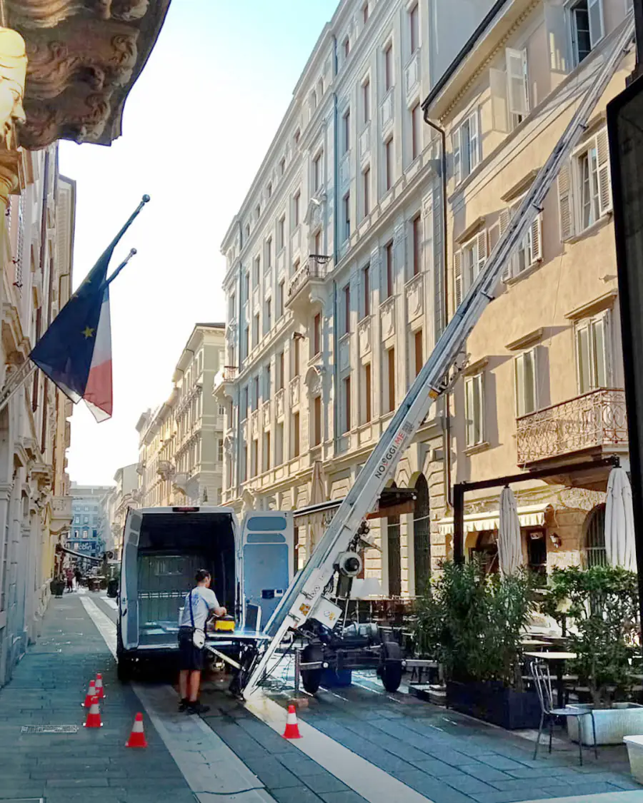 Scala elevatrice appoggiata a un palazzo del centro di Trieste, in una via pedonale, accanto al furgone e a un addetto al lavoro